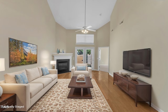 2513 Asher View Ct, Raleigh, NC 27606 - living area with high vaulted ceiling, wood finished floors, a glass covered fireplace, ceiling fan, and baseboards