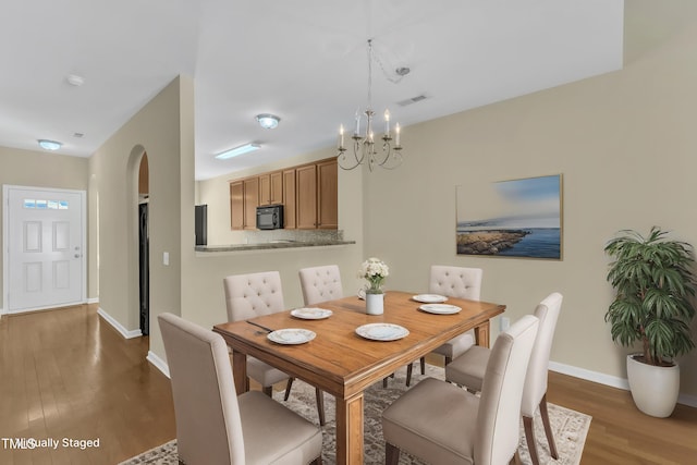 2513 Asher View Ct, Raleigh, NC 27606 - dining area with wood finished floors, a chandelier, baseboards, and arched walkways
