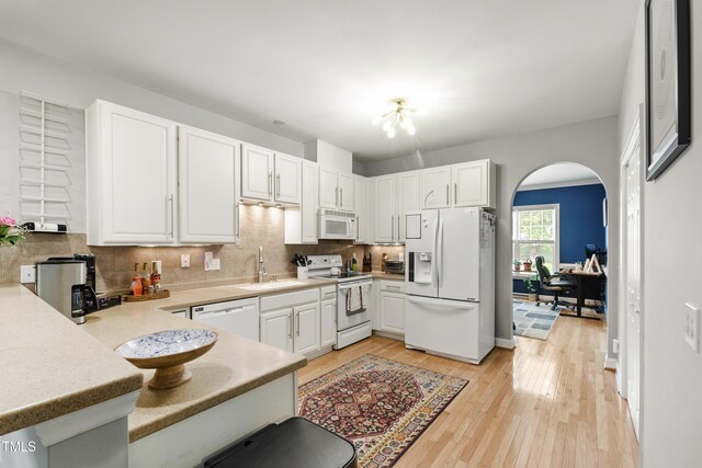 3821 La Costa Way, Raleigh, NC 27610 - kitchen featuring white appliances, a sink, arched walkways, white cabinets, and light wood-style flooring
