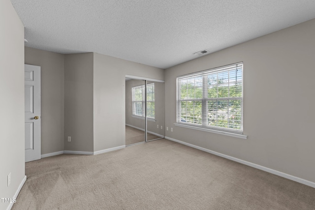 unfurnished bedroom with baseboards, carpet flooring, a textured ceiling, and a closet