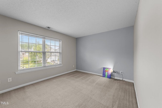 carpeted empty room featuring a textured ceiling and baseboards