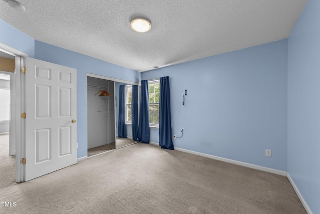 unfurnished bedroom featuring a textured ceiling, carpet, a closet, and baseboards