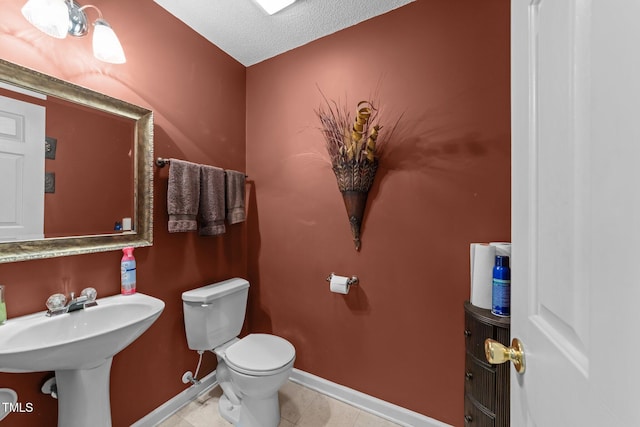 bathroom featuring toilet, a textured ceiling, and baseboards