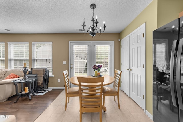 dining room featuring a textured ceiling, plenty of natural light, a chandelier, baseboards, and light tile patterned floors