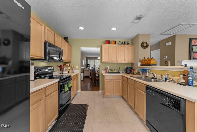 kitchen featuring black appliances, light brown cabinets, light countertops, a sink, and light tile patterned floors