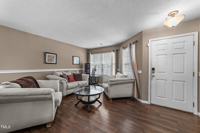 living room featuring dark wood-style flooring, a textured ceiling, and baseboards