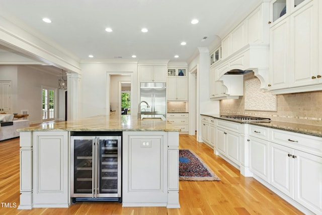 238 Michelangelo Way, Cary, NC 27518 - kitchen featuring beverage cooler, stainless steel appliances, a spacious island, a sink, and light wood-style floors