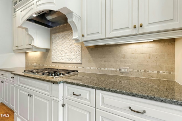238 Michelangelo Way, Cary, NC 27518 - kitchen with stainless steel gas cooktop, custom exhaust hood, white cabinetry, and decorative backsplash