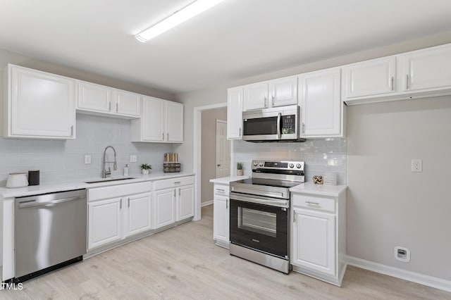 3204 Winfield Ct, Raleigh, NC 27610 - kitchen with stainless steel appliances, a sink, light wood-type flooring, tasteful backsplash, and white cabinetry