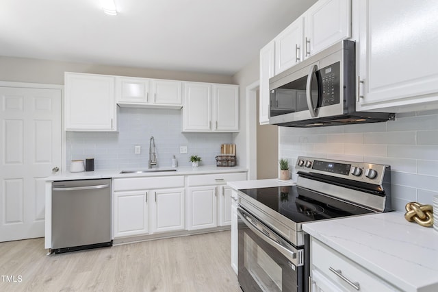 3204 Winfield Ct, Raleigh, NC 27610 - kitchen featuring appliances with stainless steel finishes, a sink, backsplash, and light wood-style flooring
