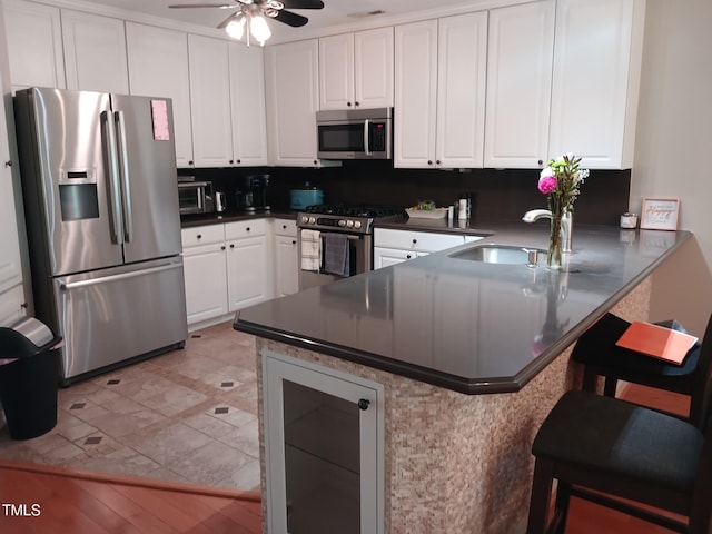 631 Springfork Dr, Cary, NC 27513 - kitchen featuring stainless steel appliances, a sink, a peninsula, white cabinetry, and dark countertops