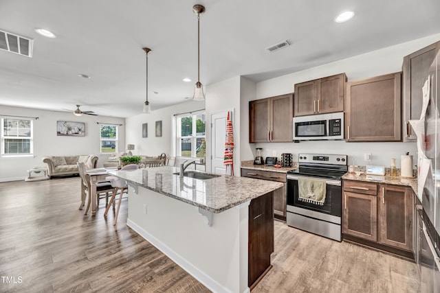 6760 Longitude Cir, Sims, NC 27880 - kitchen with stainless steel appliances, a sink, light wood finished floors, a kitchen breakfast bar, and recessed lighting