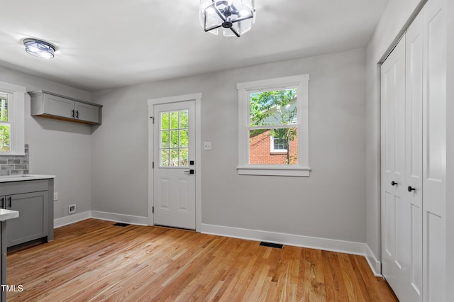833 Brigham Rd, Raleigh, NC 27610 - laundry area featuring baseboards, light wood-style flooring, and a chandelier