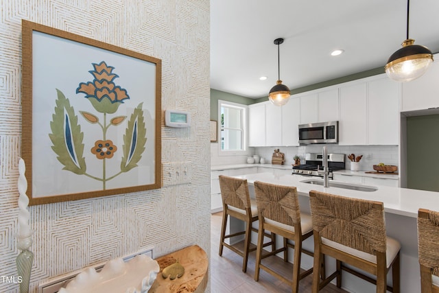 1408 Sawyer Rd Unit 103, Raleigh, NC 27610 - kitchen featuring appliances with stainless steel finishes, light countertops, a kitchen breakfast bar, hanging light fixtures, and tasteful backsplash