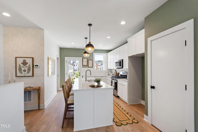 1408 Sawyer Rd Unit 103, Raleigh, NC 27610 - kitchen with appliances with stainless steel finishes, white cabinets, light wood-style floors, a kitchen island with sink, and recessed lighting