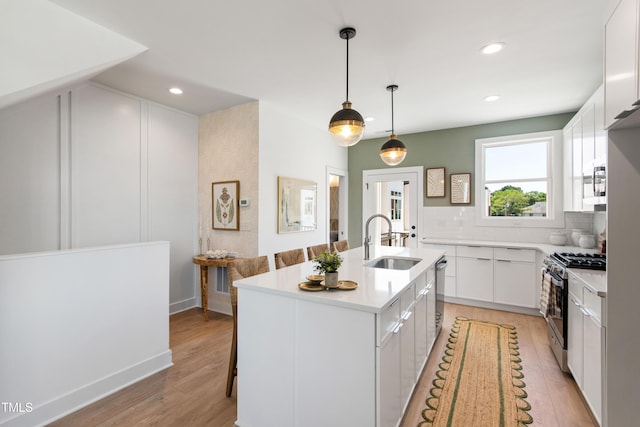 1408 Sawyer Rd Unit 103, Raleigh, NC 27610 - kitchen featuring stainless steel appliances, backsplash, white cabinets, light wood-type flooring, and light countertops