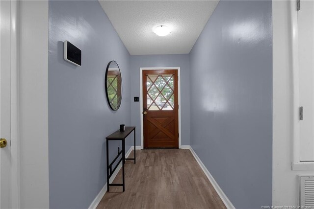 3855 Sturbridge Dr, Hope Mills, NC 28348 - doorway to outside with wood finished floors, baseboards, and a textured ceiling
