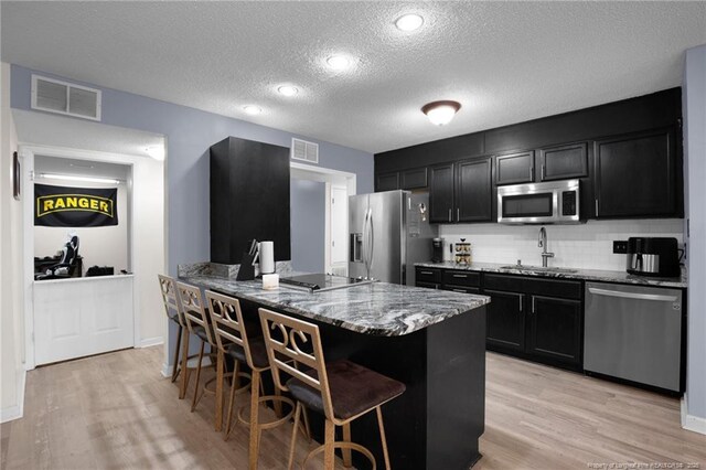 3855 Sturbridge Dr, Hope Mills, NC 28348 - kitchen featuring appliances with stainless steel finishes, a sink, dark cabinets, stone countertops, and a textured ceiling