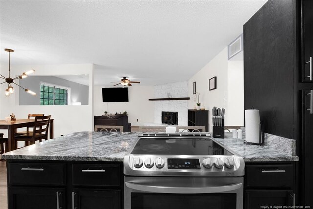 3855 Sturbridge Dr, Hope Mills, NC 28348 - kitchen with stainless steel electric stove, dark cabinetry, ceiling fan, and a chandelier