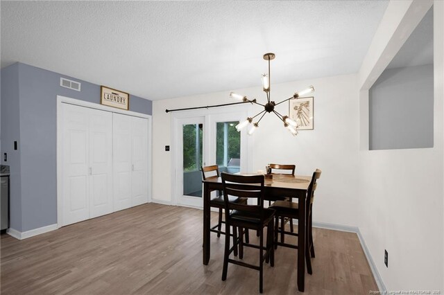 3855 Sturbridge Dr, Hope Mills, NC 28348 - dining space featuring a chandelier, wood finished floors, baseboards, and a textured ceiling