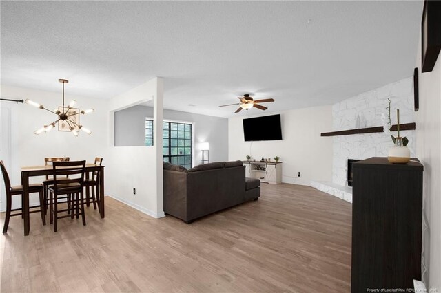 3855 Sturbridge Dr, Hope Mills, NC 28348 - living room featuring wood finished floors, a ceiling fan, a stone fireplace, and a chandelier