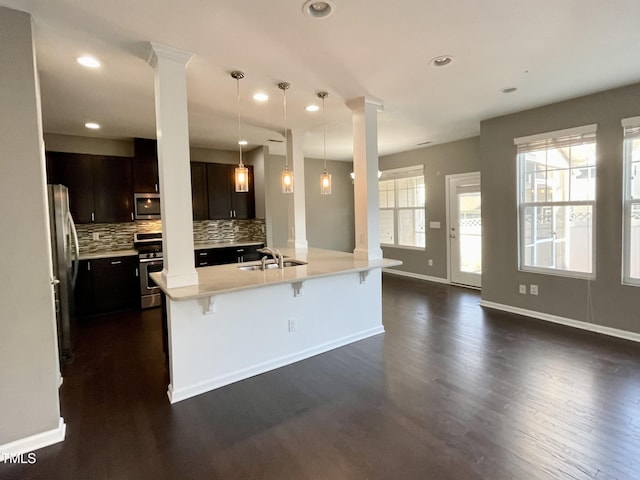 7241 Terregles Dr, Raleigh, NC 27617 - kitchen with appliances with stainless steel finishes, decorative columns, a sink, a breakfast bar area, and dark wood finished floors