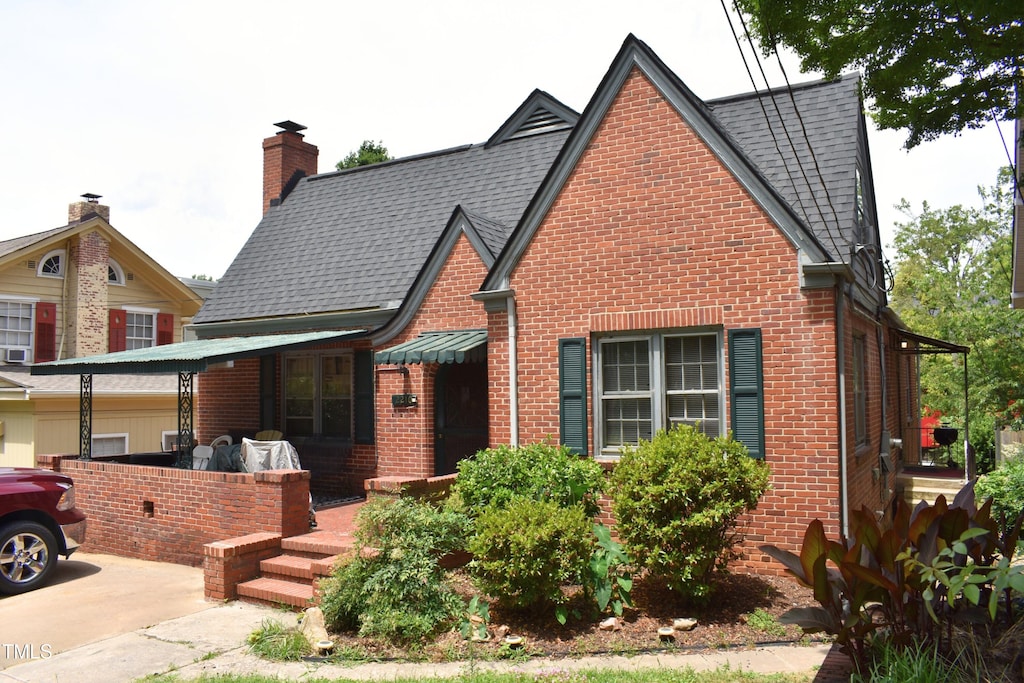 2210 Hope St, Raleigh, NC 27607 - tudor home with brick siding, a shingled roof, and a chimney