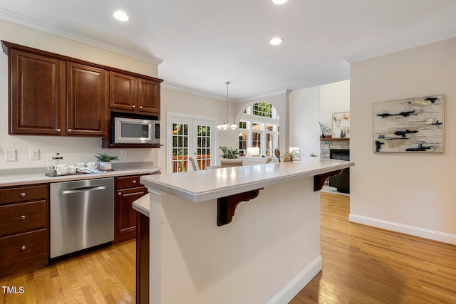 2628 Hunters Meadow Ln, Raleigh, NC 27606 - kitchen with appliances with stainless steel finishes, french doors, light countertops, a stone fireplace, and light wood-style flooring
