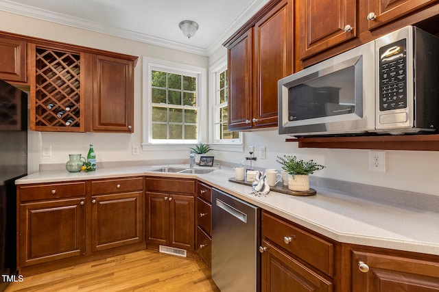 2628 Hunters Meadow Ln, Raleigh, NC 27606 - kitchen with appliances with stainless steel finishes, light wood finished floors, light countertops, and crown molding