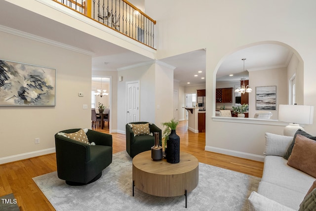 2628 Hunters Meadow Ln, Raleigh, NC 27606 - living room with a chandelier, arched walkways, light wood-style floors, plenty of natural light, and ornamental molding