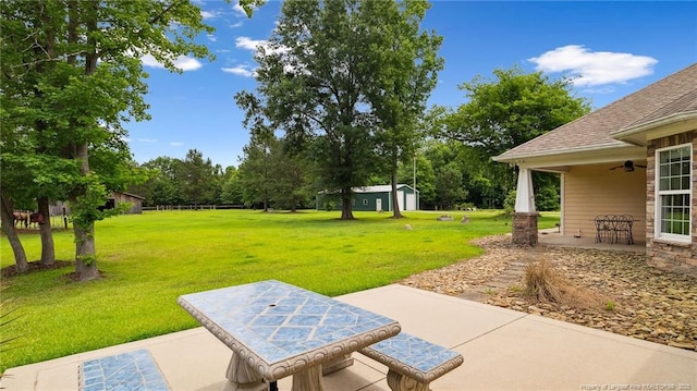 330 Wellington Rd, Saint Pauls, NC 28384 - view of grassy yard with a patio area, ceiling fan, an outbuilding, and view of wooded area