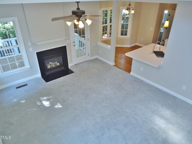 1104 Barrow Nook Ct, Apex, NC 27502 - unfurnished living room with carpet floors, a fireplace with flush hearth, baseboards, a chandelier, and a ceiling fan