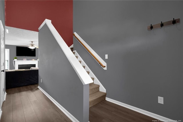 195 Cape Fear Rd, Raeford, NC 28376 - staircase featuring wood finished floors, a ceiling fan, a fireplace, and baseboards
