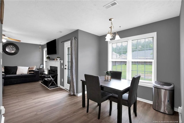 195 Cape Fear Rd, Raeford, NC 28376 - dining room with wood finished floors, baseboards, a textured ceiling, a fireplace, and a ceiling fan