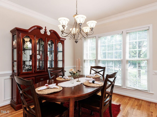 313 Hardwick Dr, Durham, NC 27713 - dining room featuring crown molding, a chandelier, a wainscoted wall, light wood-style floors, and a decorative wall