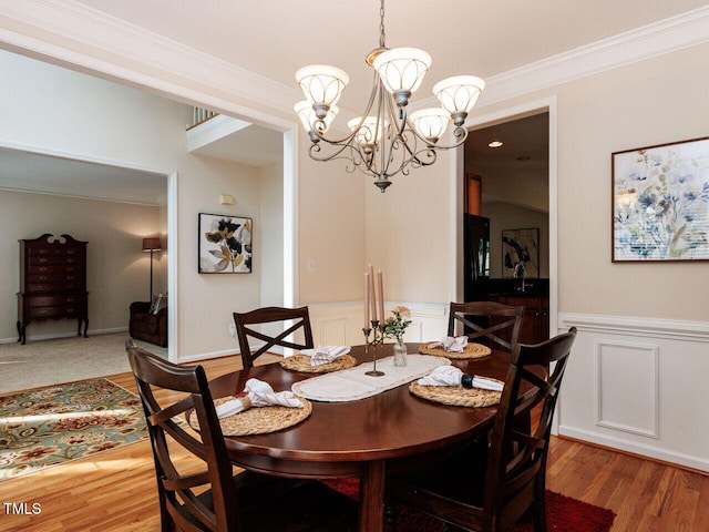 313 Hardwick Dr, Durham, NC 27713 - dining space with a chandelier, ornamental molding, wainscoting, a decorative wall, and wood finished floors