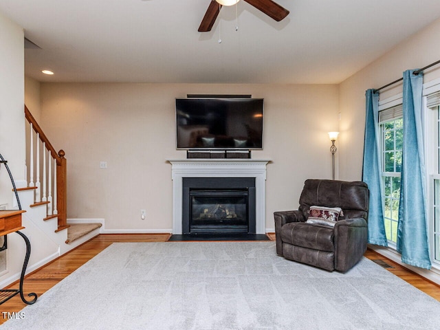 313 Hardwick Dr, Durham, NC 27713 - living area with wood finished floors, stairs, a ceiling fan, and a fireplace with flush hearth