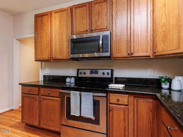 313 Hardwick Dr, Durham, NC 27713 - kitchen with stainless steel appliances, brown cabinets, light wood-type flooring, and dark stone counters