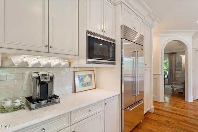801 Pinehurst Dr, Chapel Hill, NC 27517 - kitchen featuring built in appliances, ornamental molding, light wood finished floors, arched walkways, and light countertops