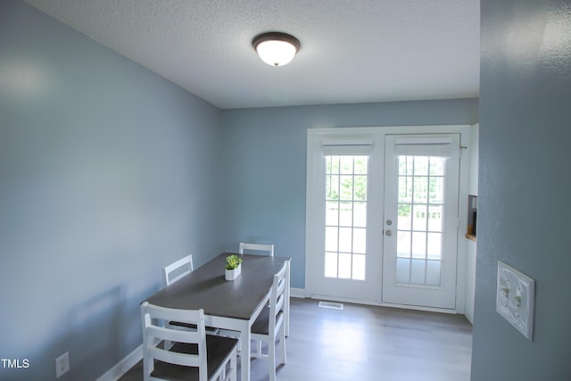 1806 Stroll Cir, Fuquay Varina, NC 27526 - dining space featuring french doors, a textured ceiling, wood finished floors, and baseboards