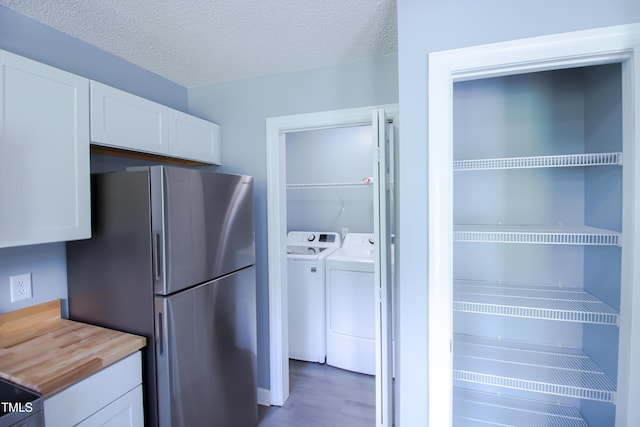 1806 Stroll Cir, Fuquay Varina, NC 27526 - kitchen featuring white cabinets, separate washer and dryer, freestanding refrigerator, butcher block counters, and a textured ceiling