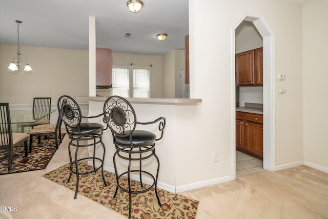 4009 Patriot Ridge Ct, Raleigh, NC 27610 - kitchen featuring light colored carpet, a kitchen breakfast bar, a chandelier, and brown cabinetry