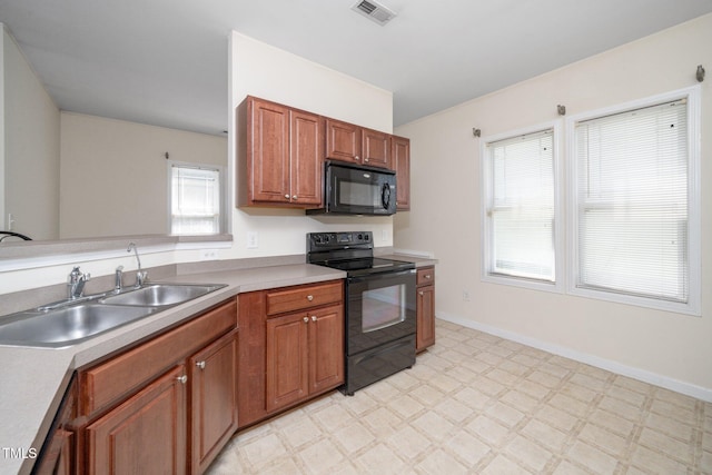 4009 Patriot Ridge Ct, Raleigh, NC 27610 - kitchen featuring black appliances, a sink, light floors, brown cabinetry, and light countertops