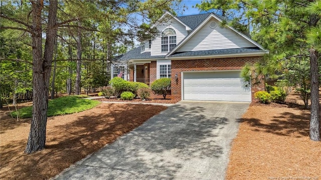 202 Juniper Creek Blvd, Pinehurst, NC 28374 - view of front of house with brick siding, driveway, a garage, and roof with shingles