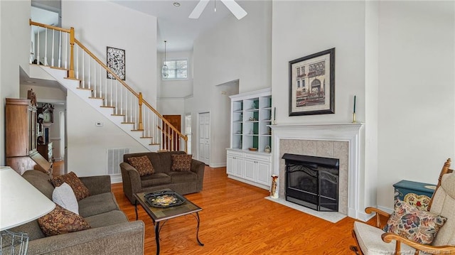 202 Juniper Creek Blvd, Pinehurst, NC 28374 - living room featuring a towering ceiling, stairs, a ceiling fan, wood finished floors, and a tile fireplace
