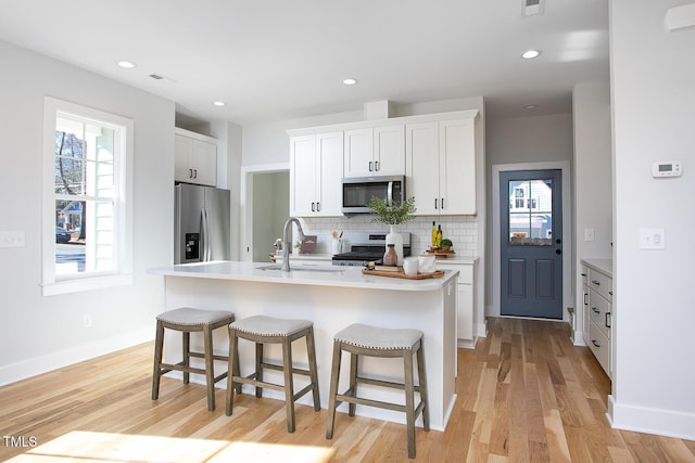 1514 W Knox St, Durham, NC 27705 - kitchen featuring stainless steel appliances, a sink, tasteful backsplash, light wood-type flooring, and white cabinets