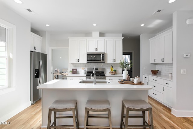1514 W Knox St, Durham, NC 27705 - kitchen featuring stainless steel appliances, tasteful backsplash, a breakfast bar area, light wood-style flooring, and recessed lighting