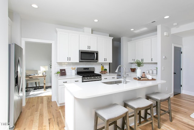 1514 W Knox St, Durham, NC 27705 - kitchen featuring appliances with stainless steel finishes, a sink, a breakfast bar, light countertops, and tasteful backsplash