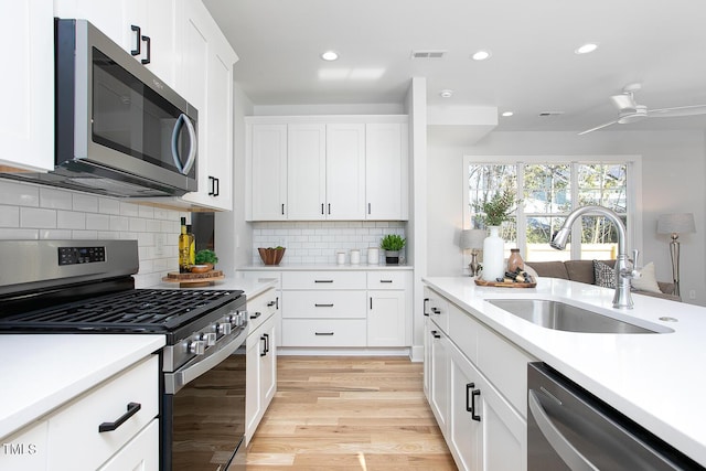 1514 W Knox St, Durham, NC 27705 - kitchen featuring appliances with stainless steel finishes, a sink, light countertops, light wood finished floors, and white cabinets