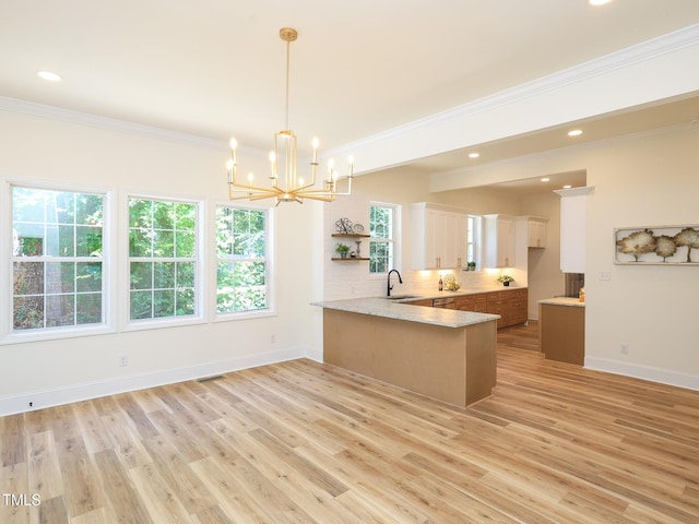 2106 University Dr, Durham, NC 27707 - kitchen featuring a sink, a peninsula, a chandelier, ornamental molding, and light wood-style flooring